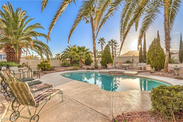 view of pool with a patio, fence, and a pool with connected hot tub