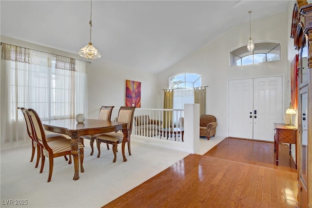 dining space featuring high vaulted ceiling, an inviting chandelier, and wood finished floors