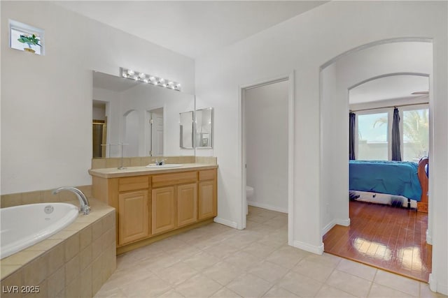 ensuite bathroom featuring a garden tub, tile patterned flooring, vanity, toilet, and ensuite bath