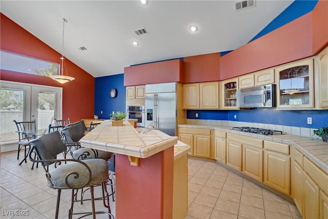 1421 Via Savona Dr, Henderson, NV 89052 - kitchen with appliances with stainless steel finishes, tile countertops, light tile patterned floors, light brown cabinetry, and high vaulted ceiling