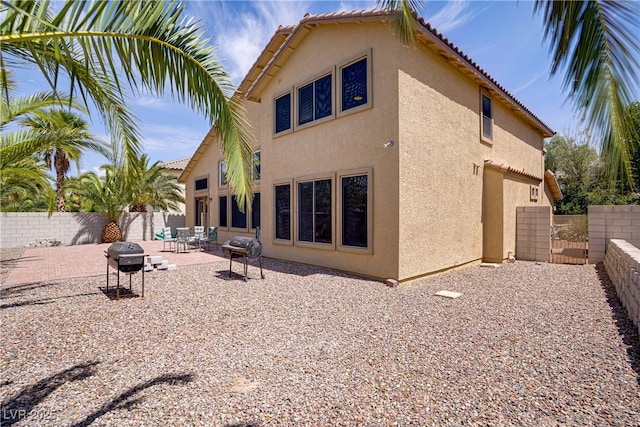 back of property with a gate, a fenced backyard, a patio area, and stucco siding
