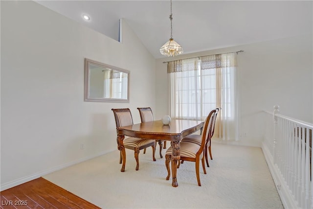 dining space with an inviting chandelier, baseboards, light wood finished floors, and lofted ceiling