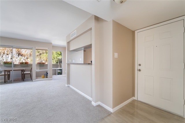 foyer featuring baseboards, carpet floors, and visible vents