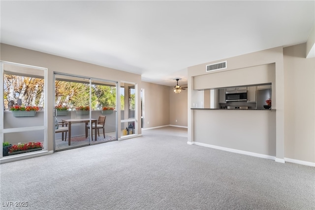 unfurnished living room featuring baseboards, ceiling fan, carpet flooring, and visible vents