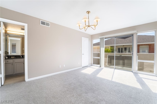 spare room featuring light colored carpet, visible vents, baseboards, a notable chandelier, and a wealth of natural light