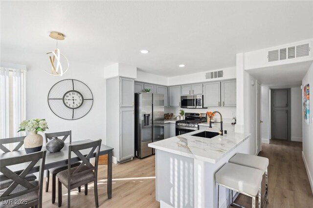 3425 E Russell Rd Unit 202, Las Vegas, NV 89120 - kitchen with stainless steel appliances, a sink, gray cabinetry, a peninsula, and light stone counters