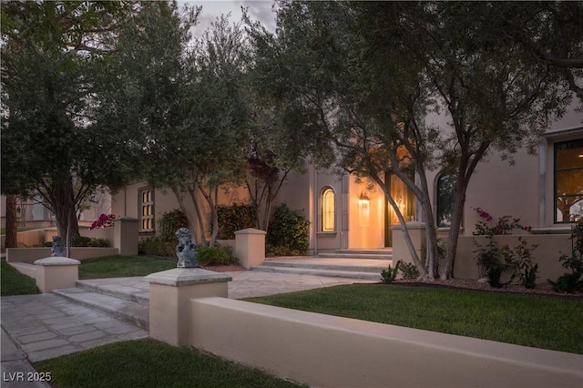 view of front of property featuring stucco siding and a front yard