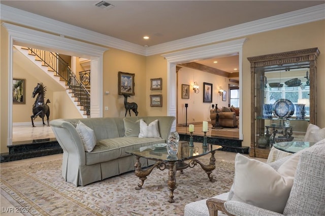 living room featuring decorative columns, visible vents, crown molding, stairway, and baseboards