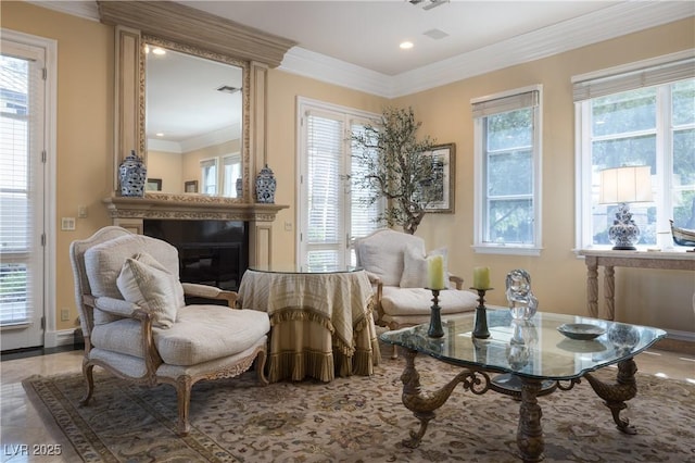 living area with recessed lighting, a glass covered fireplace, ornamental molding, and a wealth of natural light