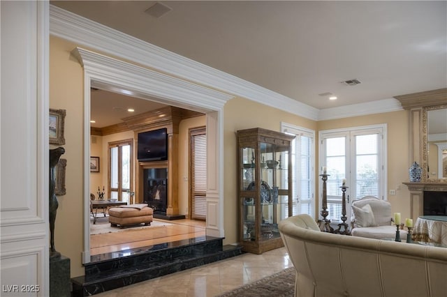 living area with crown molding, a healthy amount of sunlight, a fireplace, and visible vents