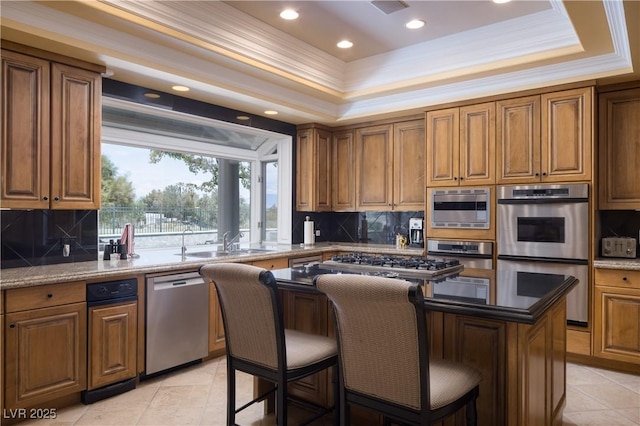kitchen with a sink, decorative backsplash, appliances with stainless steel finishes, and brown cabinets