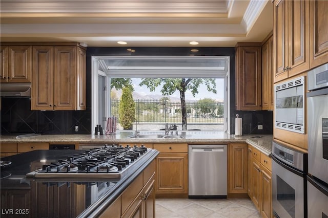 kitchen with crown molding, a sink, appliances with stainless steel finishes, and tasteful backsplash