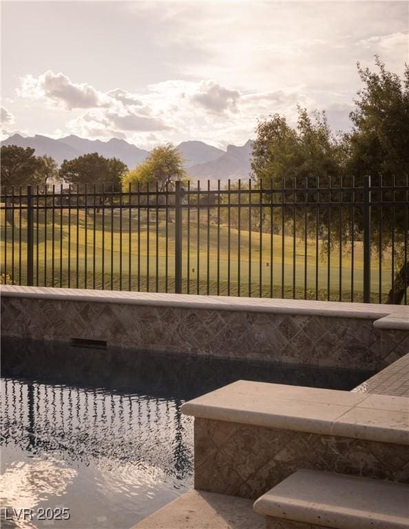 view of swimming pool with a fenced backyard and a mountain view