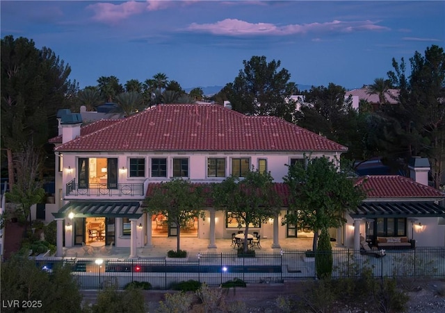 back of house featuring a tiled roof, a chimney, a patio area, fence, and a fenced in pool