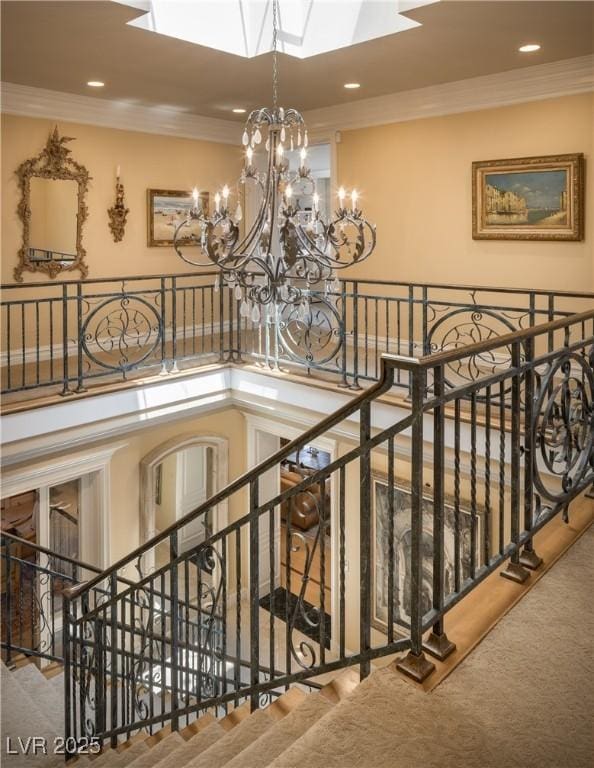 stairway featuring crown molding, carpet floors, a notable chandelier, and a skylight