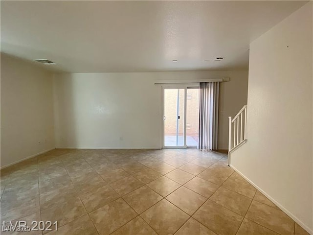 tiled empty room featuring stairs, baseboards, and visible vents