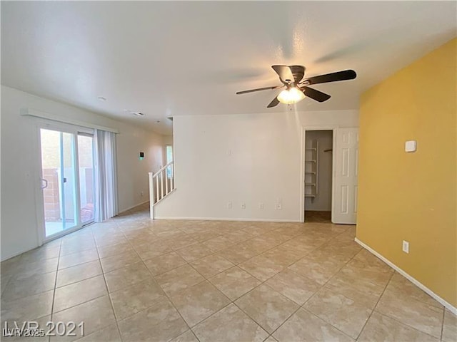 interior space with light tile patterned floors, baseboards, a ceiling fan, and stairs
