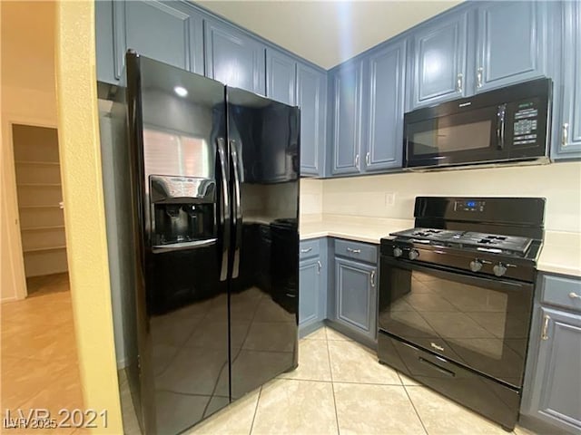 kitchen featuring light countertops, light tile patterned flooring, blue cabinetry, and black appliances