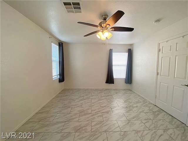 empty room with baseboards, a ceiling fan, marble finish floor, and visible vents