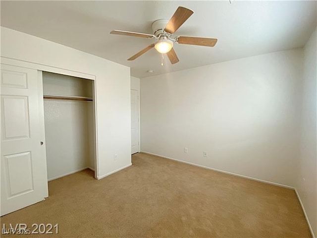 unfurnished bedroom featuring baseboards, ceiling fan, light carpet, and a closet