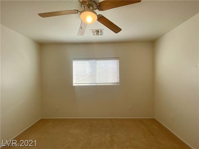 carpeted spare room featuring visible vents, a ceiling fan, and baseboards