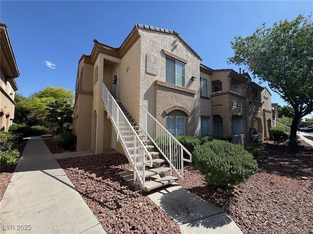 view of front facade with stairway and stucco siding