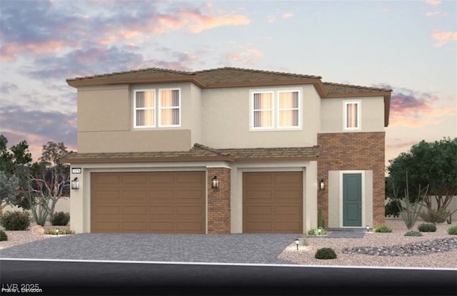 view of front of house featuring brick siding, an attached garage, decorative driveway, and stucco siding