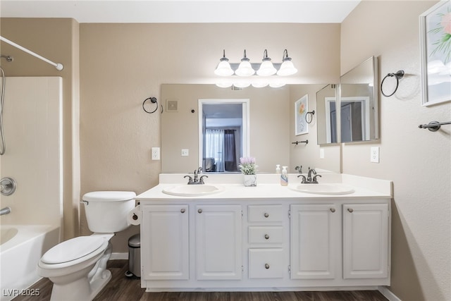 bathroom featuring double vanity, toilet, shower / bath combination, and a sink