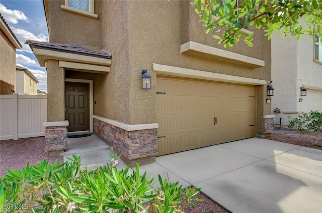 6231 Portland Treaty Ave, Las Vegas, NV 89122 - view of exterior entry with an attached garage, fence, stone siding, and stucco siding