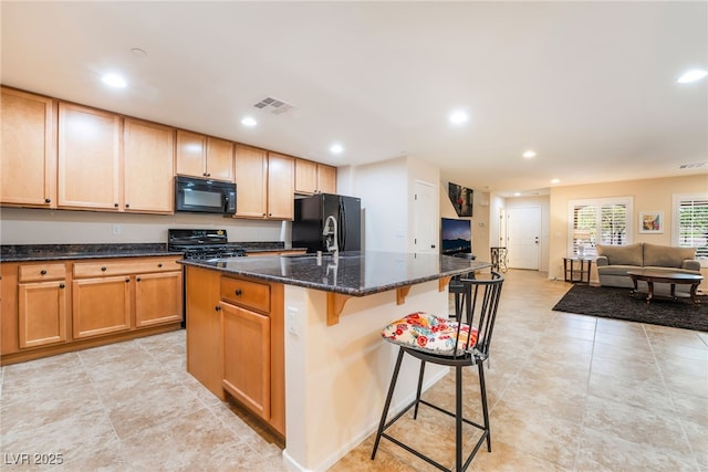 kitchen with visible vents, a breakfast bar, recessed lighting, dark stone counters, and black appliances