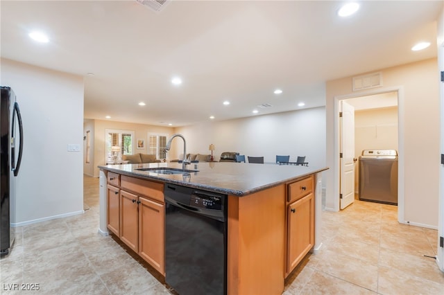 kitchen featuring washer / clothes dryer, visible vents, a sink, black appliances, and an island with sink
