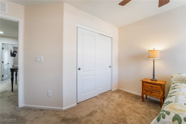 bedroom with visible vents, a closet, baseboards, light colored carpet, and a ceiling fan