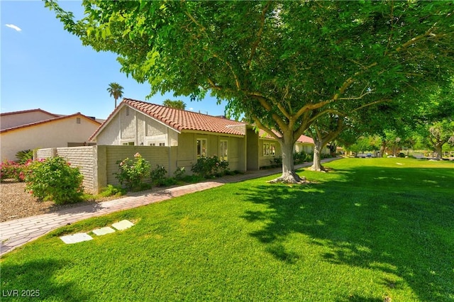 view of front of house with a front lawn, stucco siding, a tiled roof, and fence