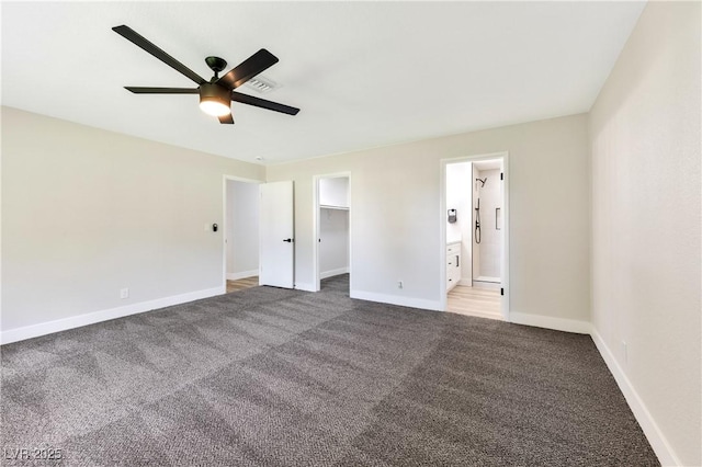 unfurnished bedroom with carpet floors, baseboards, a walk in closet, and ensuite bath