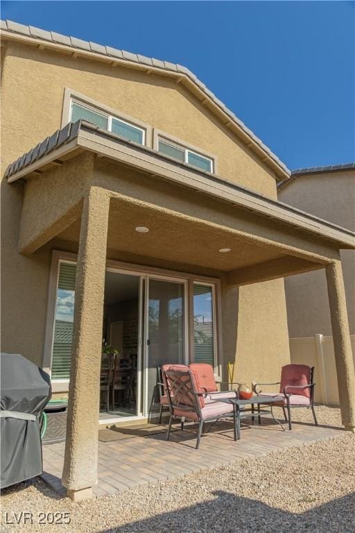 rear view of house with a patio and stucco siding