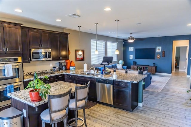 kitchen featuring ceiling fan, stainless steel appliances, open floor plan, a peninsula, and visible vents