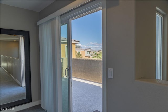 doorway featuring baseboards and carpet flooring