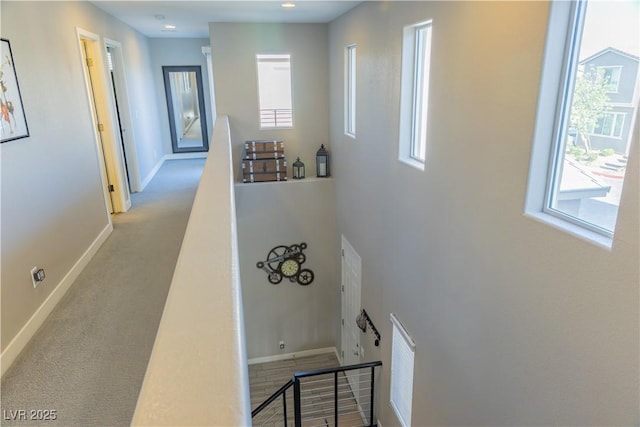 corridor featuring baseboards, carpet, and an upstairs landing