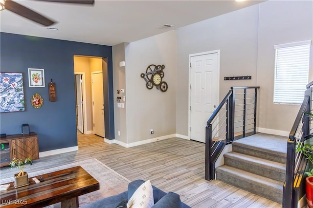 interior space featuring baseboards, a ceiling fan, and light wood finished floors