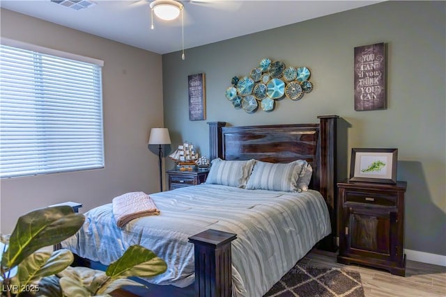 bedroom with a ceiling fan, baseboards, visible vents, and wood finished floors