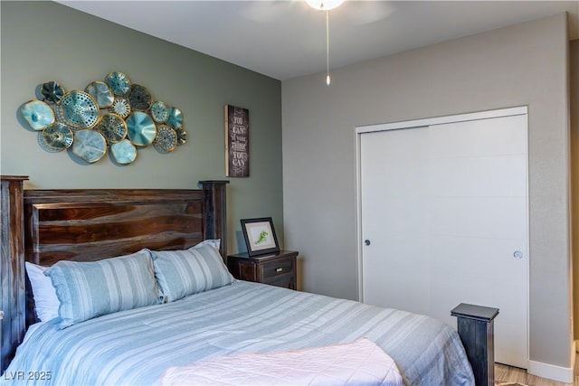 bedroom featuring a ceiling fan, light wood-style floors, and a closet