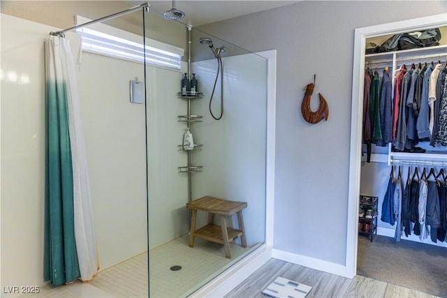 full bathroom with a spacious closet and a stall shower