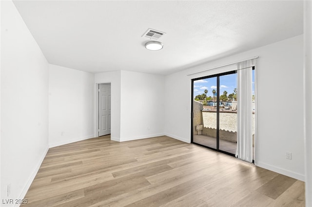 empty room with baseboards, visible vents, and light wood-style floors