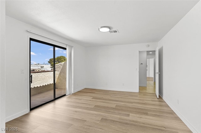 empty room featuring baseboards, visible vents, and light wood-style flooring