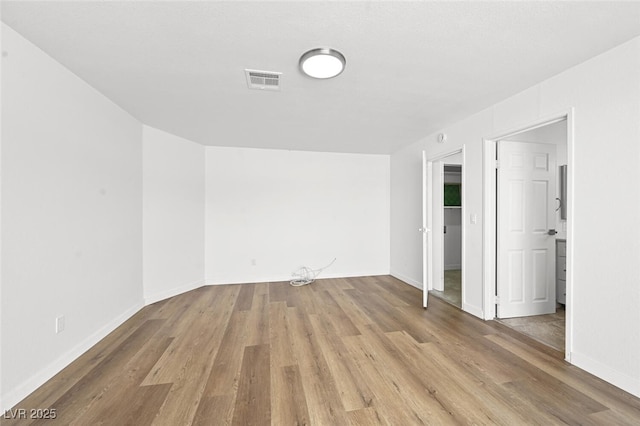 empty room with visible vents, baseboards, and wood finished floors