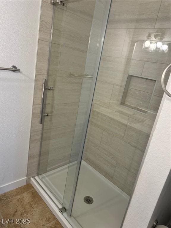 bathroom with baseboards and a shower stall