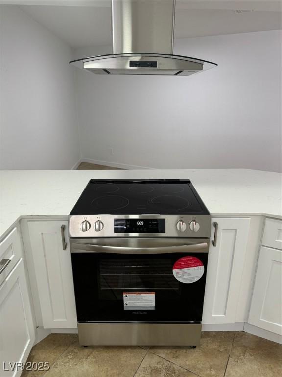 room details with light countertops, stainless steel electric range, white cabinets, and wall chimney range hood