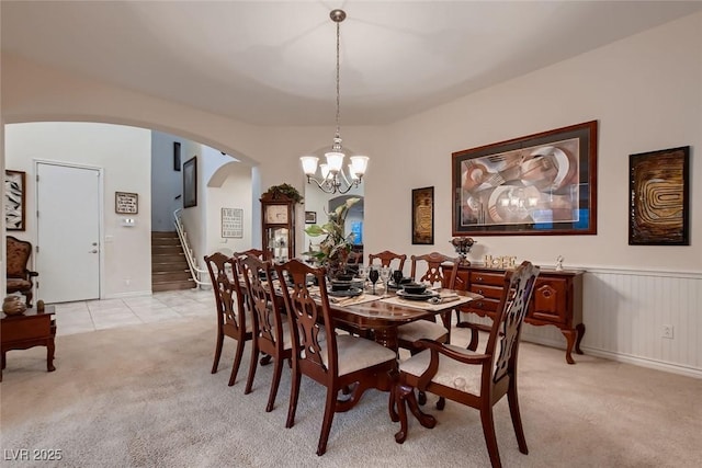 6750 Quapaw St, Las Vegas, NV 89149 - dining space featuring light carpet, wainscoting, arched walkways, a chandelier, and stairs