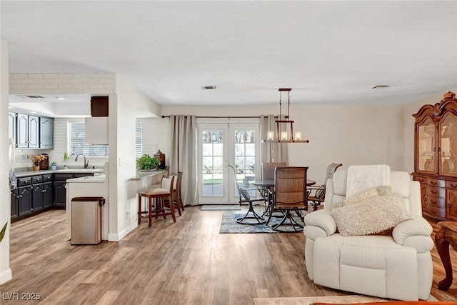 sitting room with light wood-style floors, baseboards, and visible vents