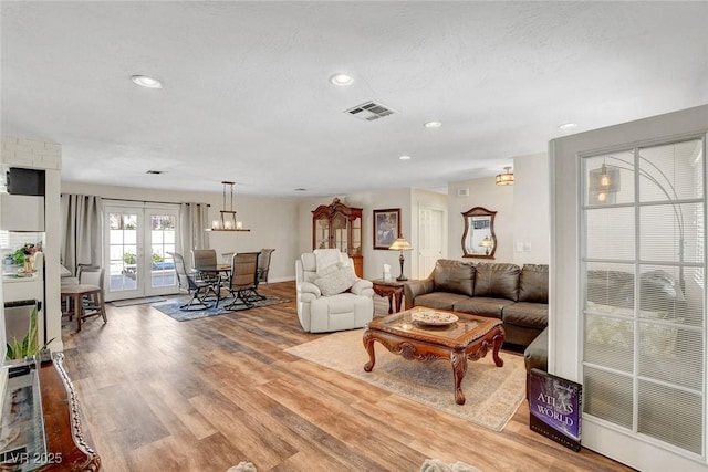 living area with a chandelier, recessed lighting, baseboards, wood finished floors, and visible vents